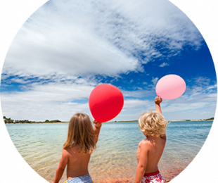 Niños de espalda en la playa con globos